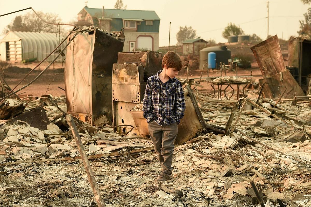 Jeremie Saylors, 11, walks through the burned remains of his home in Paradise, California on November 18, 2018. - The family lost a home in the same spot to a fire 10 years prior. (Photo by Josh Edelson / AFP)