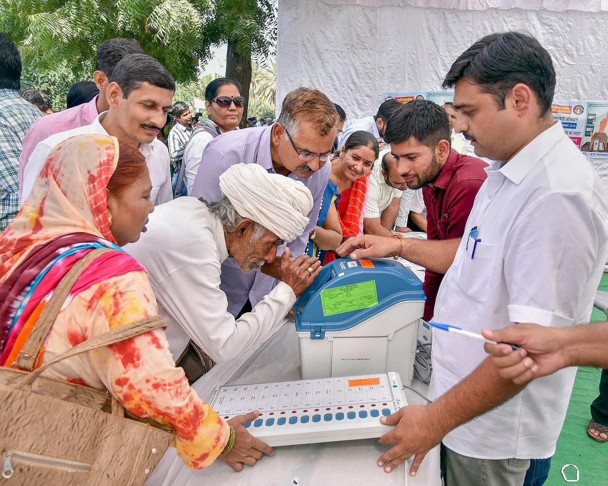 Electoral officials demonstrate how to use an Electronic Voting Machine (EVM) and Voter-Verified Paper Audit Trail (VVPAT) to locals during a voter awareness programme ahead of Rajasthan State Assembly elections, in Bikaner. (PTI Photo)