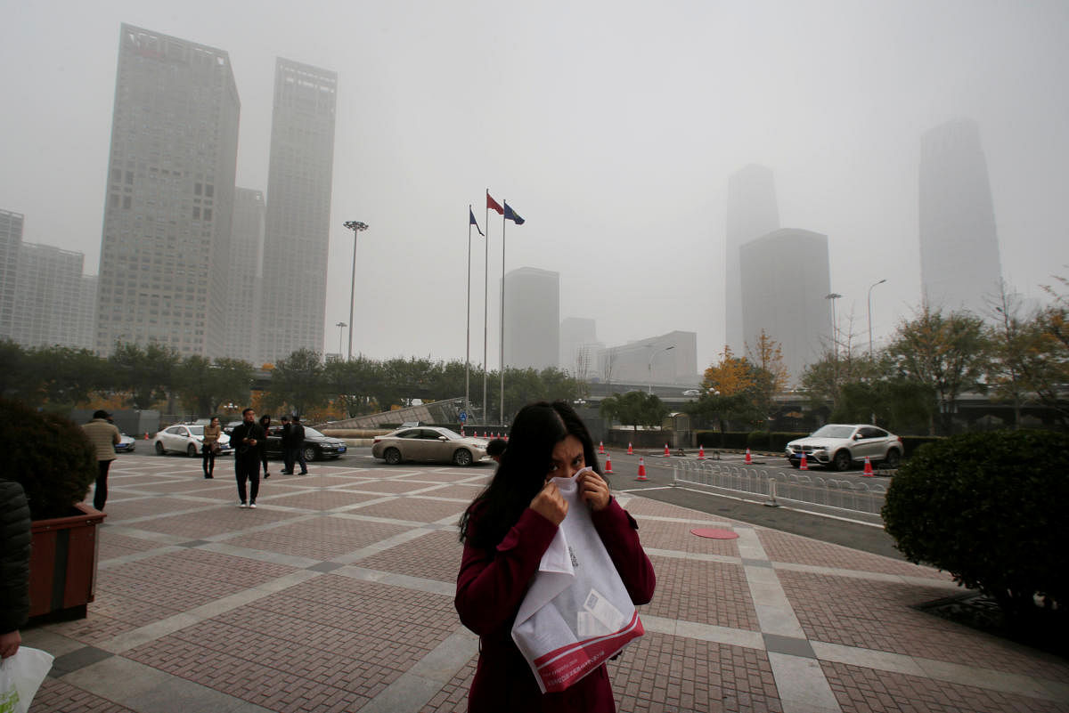 A woman covers her nose as she walks in the central business district on a polluted day after a yellow alert was issued for smog, in Beijing, China. (REUTERS File Photo)
