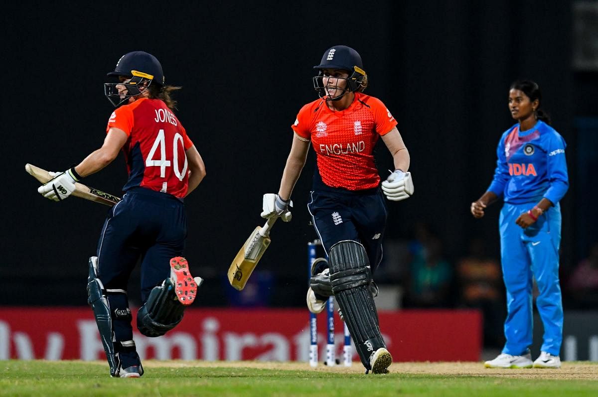 Amy Jones (L) and Nat Sciver (C) of England 50 runs partnership as Dayalan Hemalatha (R) looks on during the ICC Women's World T20 2nd semi-final match between England and India at Sir Vivian Richards Cricket Ground, North Sound, Antigua and Barbuda, on November 22, 2018. (Photo by Randy Brooks / AFP)