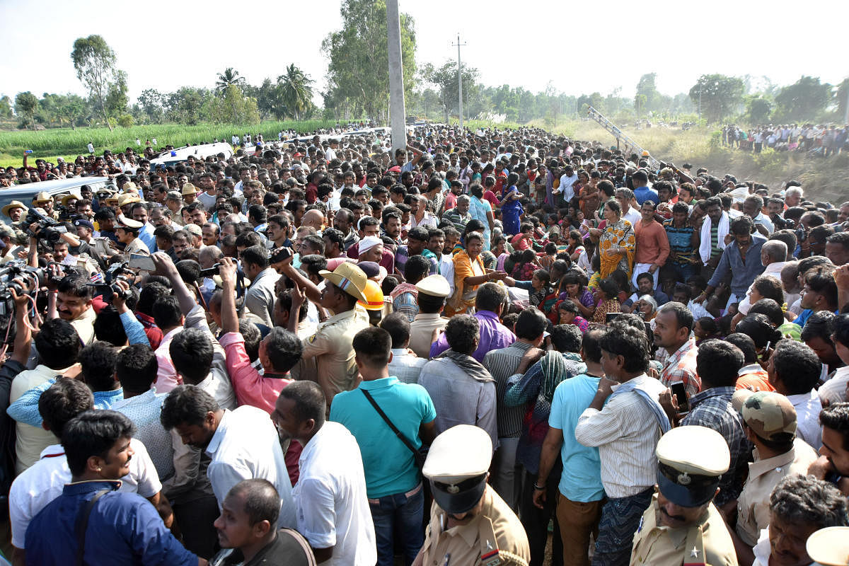 People gather near the Visvesvaraya Canal, where a bus plunged at Kanaganamaradi in Pandavapura taluk, in Mandya district, on Saturday.