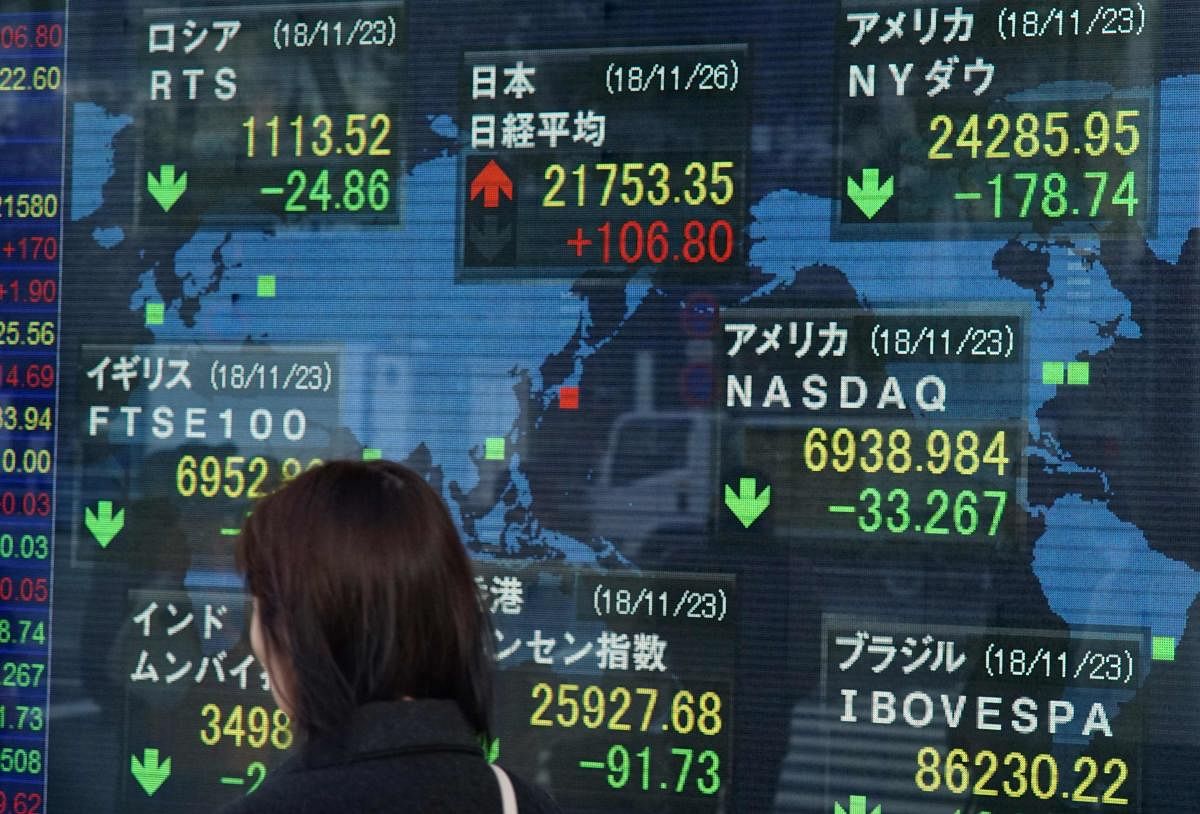 A woman walks past a stock indicator board showing the share prices of the Tokyo Stock Exchange (C, top) and other major markets in Tokyo on November 26, 2018. - Tokyo stocks opened slightly higher November 26 as investors looked beyond negative news such