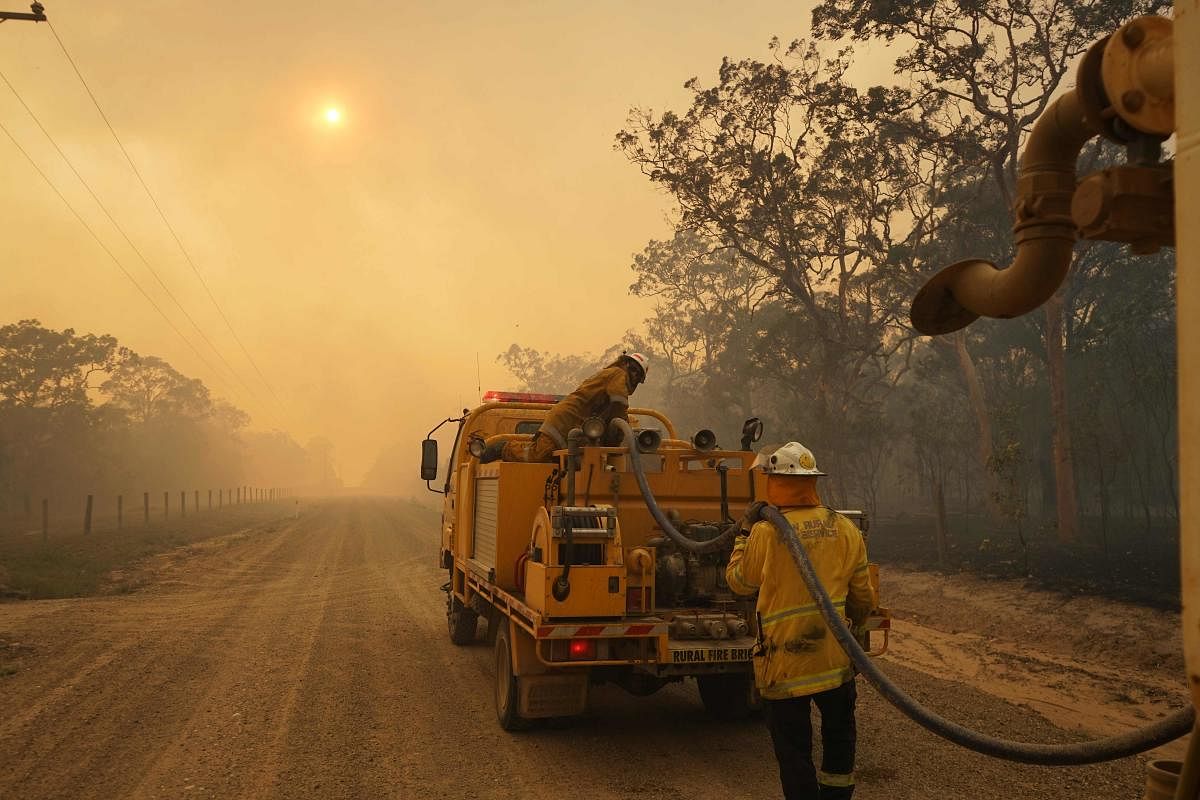 Firefighters refill their water from a water tanker in Pacific Drive in Deepwater National Park area of Queensland on November 28, 2018. AFP