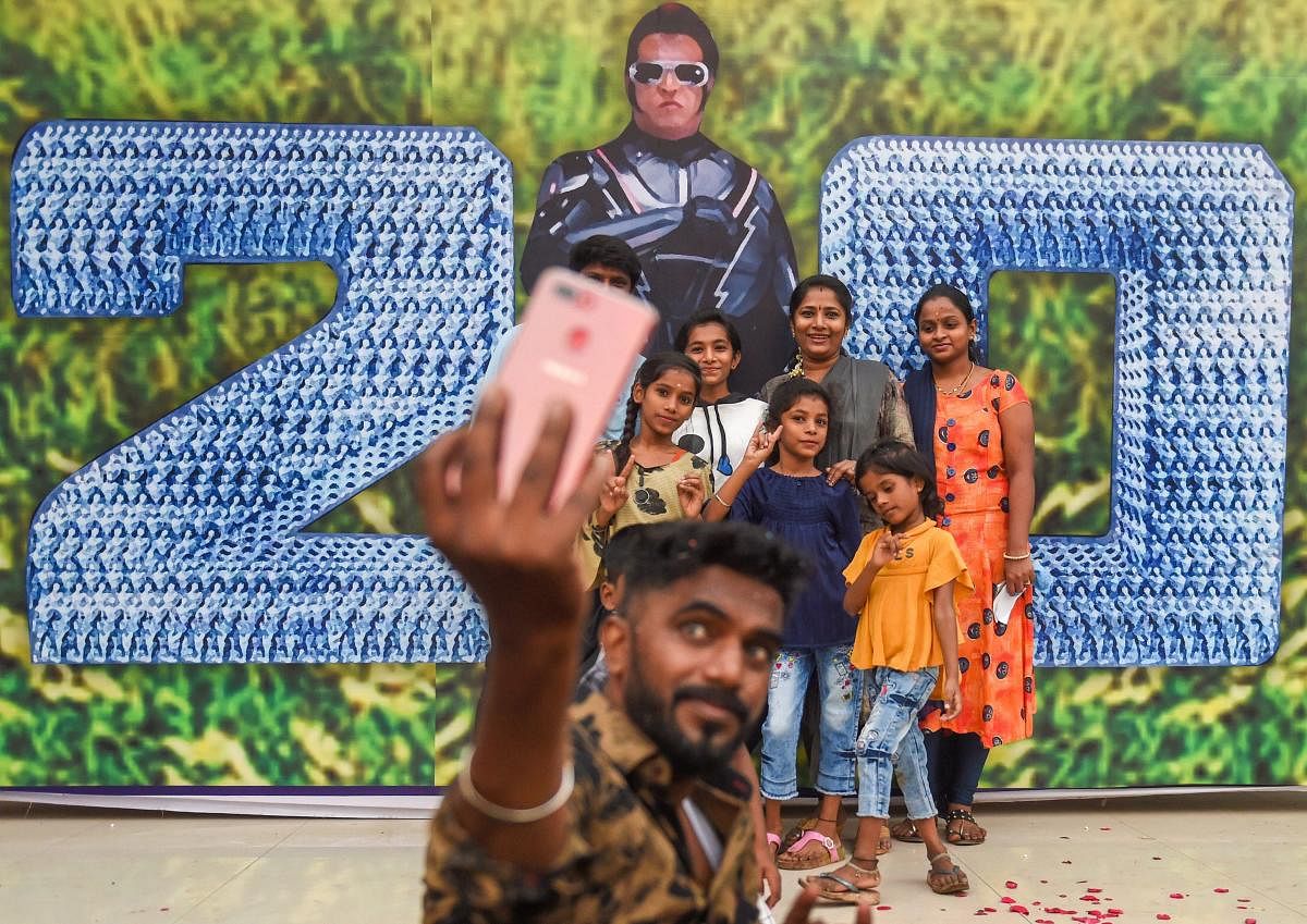 People take a selfie with the poster of Tamil actor Rajinikanth's movie '2.0' in Mumbai.  PTI photo