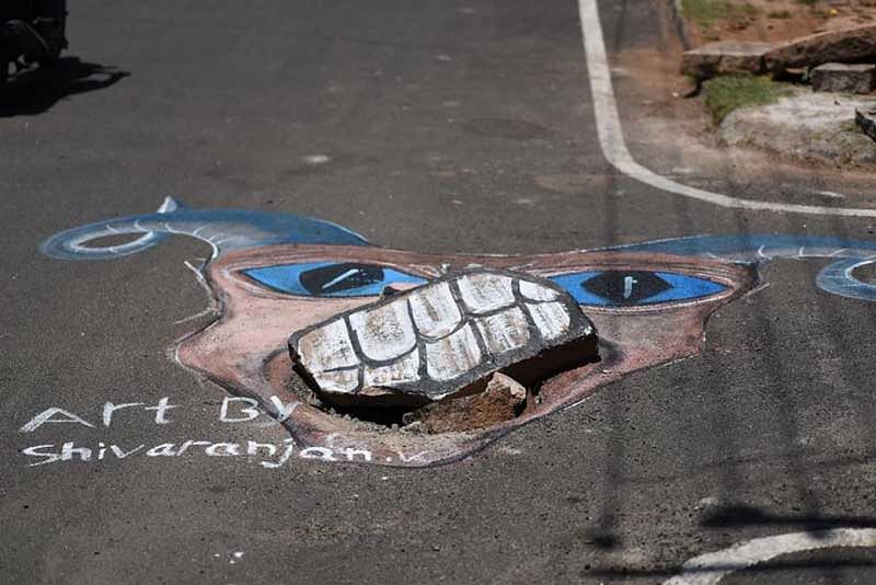 Halaguru Shivaranjan, who is pursuing his bachelors in Visual Arts at Charmarajendra Academy Of Visual Arts (CAVA), has been drawing the attention of authorities through his paintings that highlight the potholes and uncovered manholes. (DH Photo)