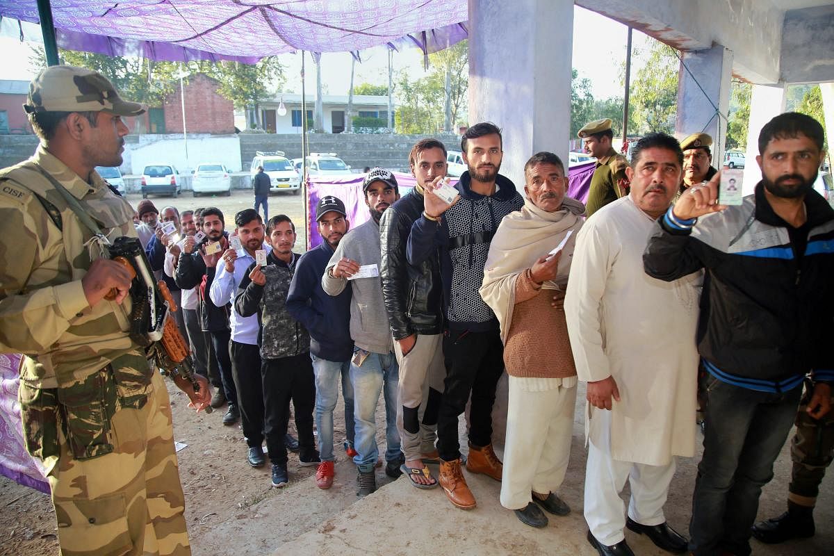 Voters stand in a queue at a polling station during the 2nd phase of the panchayat elections at Tikri village, in Udhampur district, on Tuesday. PTI