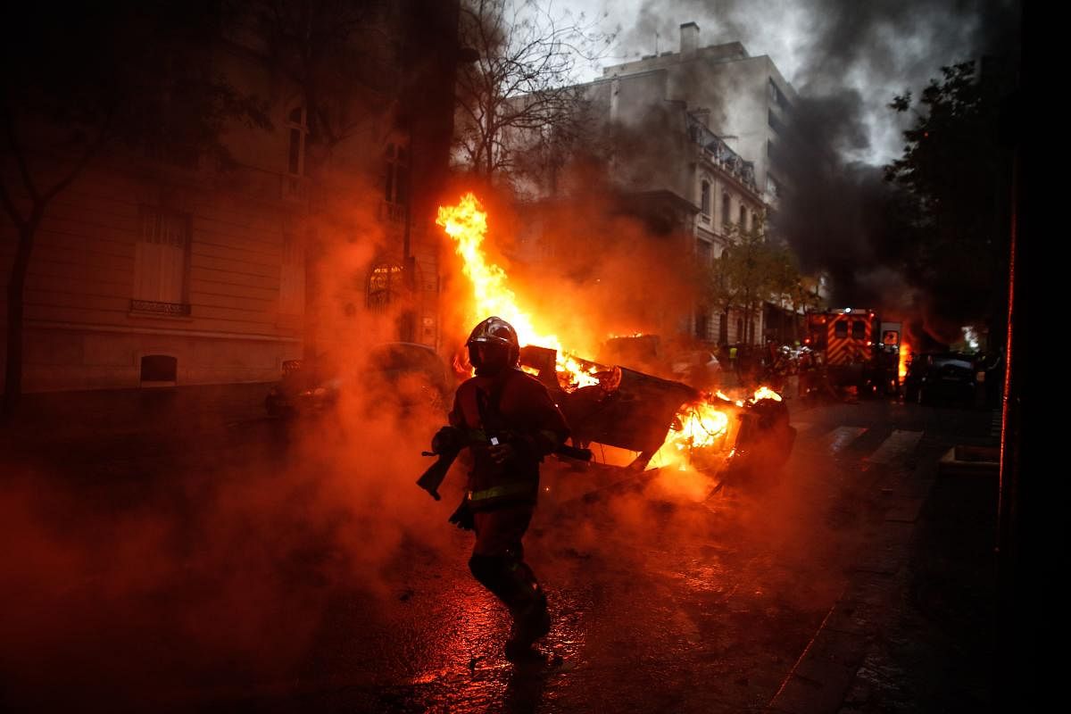 Firemen are at work to extinguish a burning car on the sideline of a demonstration by Yellow vests (Gilets jaunes) protesters against rising oil prices and living costs, on December 1, 2018 in Paris. (Photo by Abdulmonam EASSA / AFP)