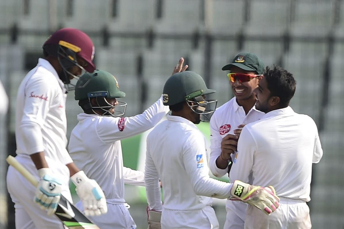 Mehidy Hasan (right) celebrates with team-mates after the dismissal of Devendra Bishoo in Dhaka on Sunday. AFP