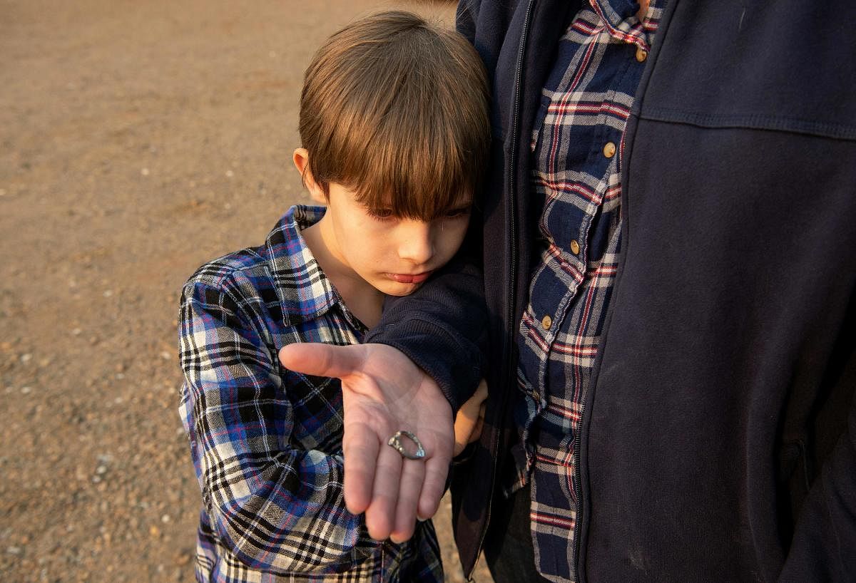 Jacob Saylors, 11, looks at the wedding ring his mother Zeatra Saylor found in the burned remains of their home in Paradise, California on November 18, 2018. - The family lost a home in the same spot to a fire 10 years prior. (AFP File Photo)