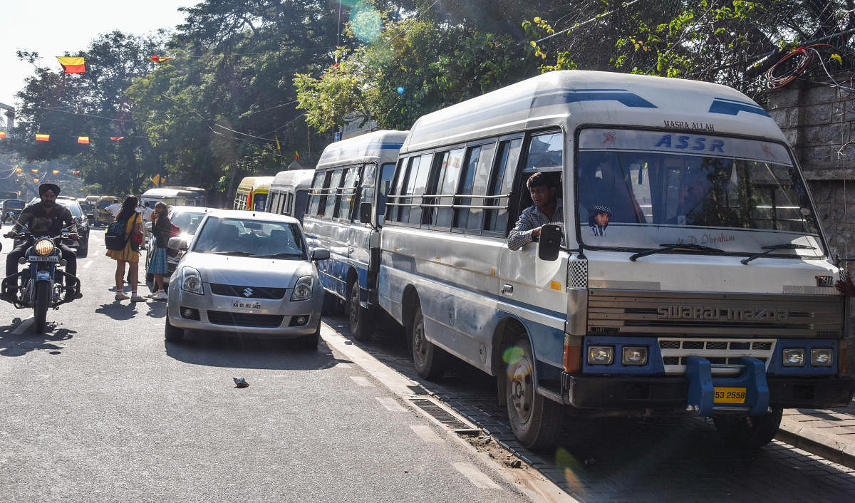 Serpentine queues: School buses, vans and other private vehicles parked haphazardly outside a school on Residency Road on Monday. DH Photo/S K Dinesh)