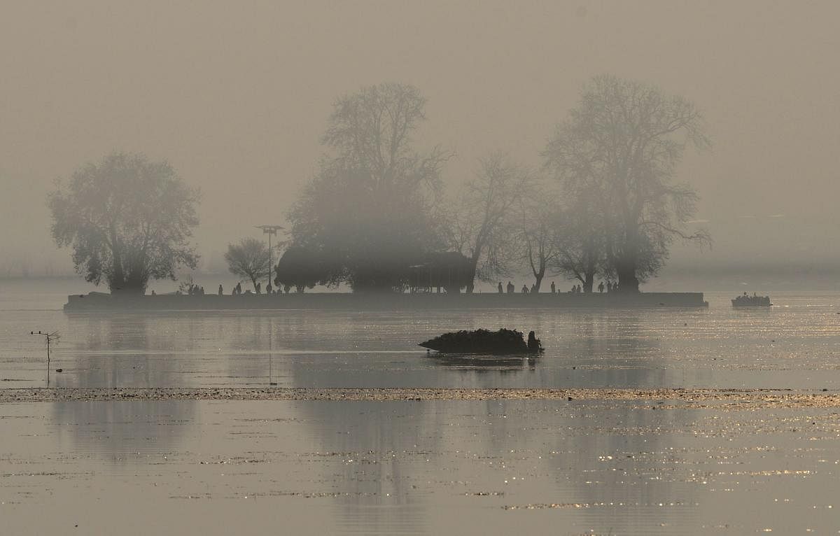 ashmiri Muslims ride a shikara boat in Dal lake amidst a dense fog in Srinagar. (AFP photo)