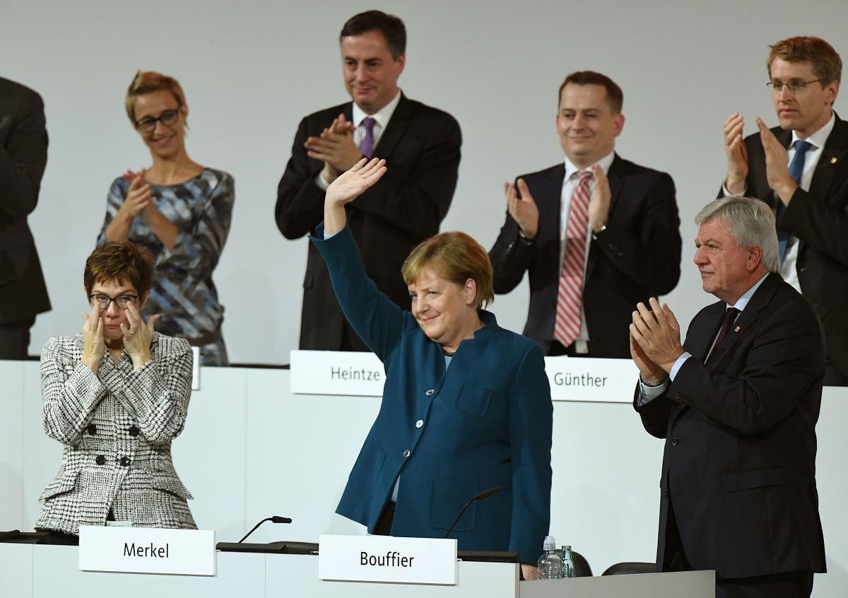 German Chancellor and leader of the CDU Angela Merkel greets the audience as she is applauded by CDU Secretary General and Hesse's State Premier and CDU Deputy Chairman Volker Bouffier during a CDU congress on December 7, 2018 at a fair hall in Hamburg, northern Germany. AFP