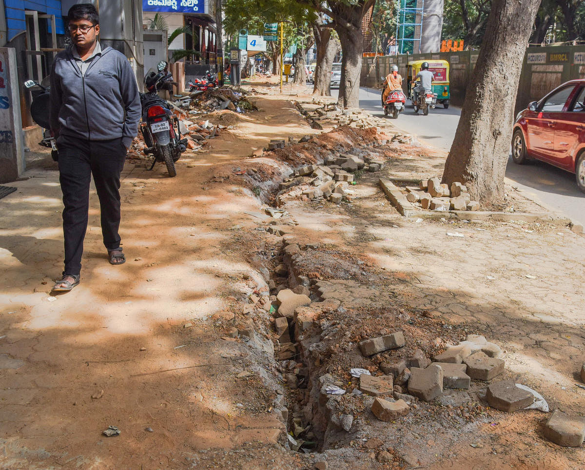 Pedestrian walks along  an under construction footpath in Jayanagar, Bengaluru. DH photo by  S K Dinesh.