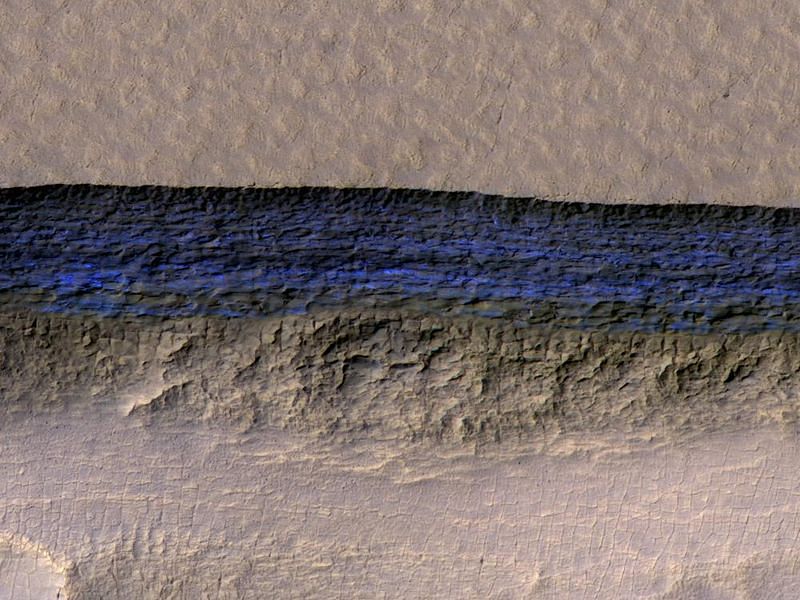 A cross-section of underground ice is exposed at the steep slope that appears bright blue in this enhanced-color view from the HiRISE camera on NASA's Mars Reconnaissance Orbiter. The scene is about 550 yards wide. The scarp drops about 140 yards from the level ground in the upper third of the image. Credits: NASA/JPL-Caltech/UA/USGS