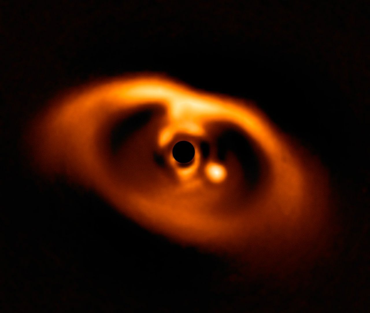This spectacular image from the SPHERE instrument on ESO's Very Large Telescope is the first clear image of a planet caught in the very act of formation around the dwarf star PDS 70. The planet stands clearly out, visible as a bright point to the right of the centre of the image, which is blacked out by the coronagraph mask used to block the blinding light of the central star. ESO/A. Müller et al. ESO/A. Müller et al.