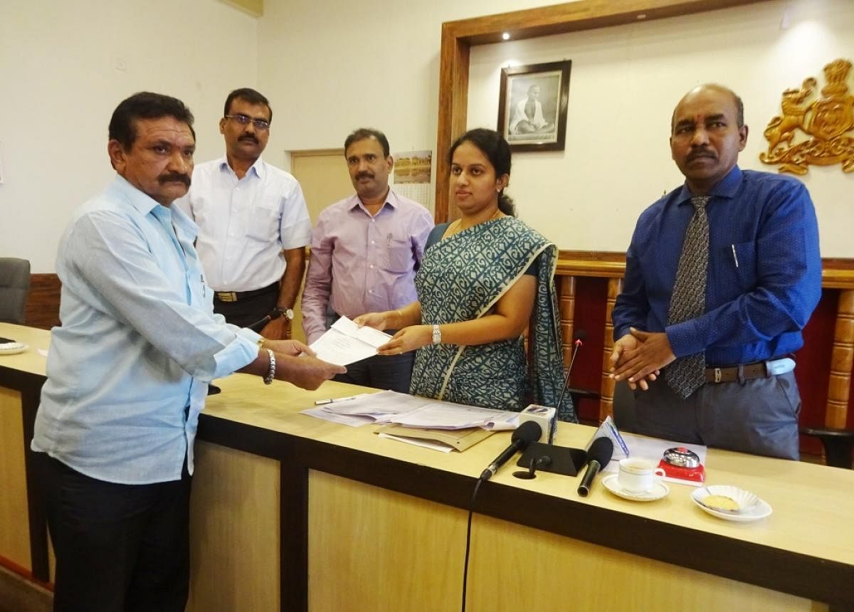 Deputy Commissioner P I Sreevidya symbolically hands over a token to a farmer on Thursday.