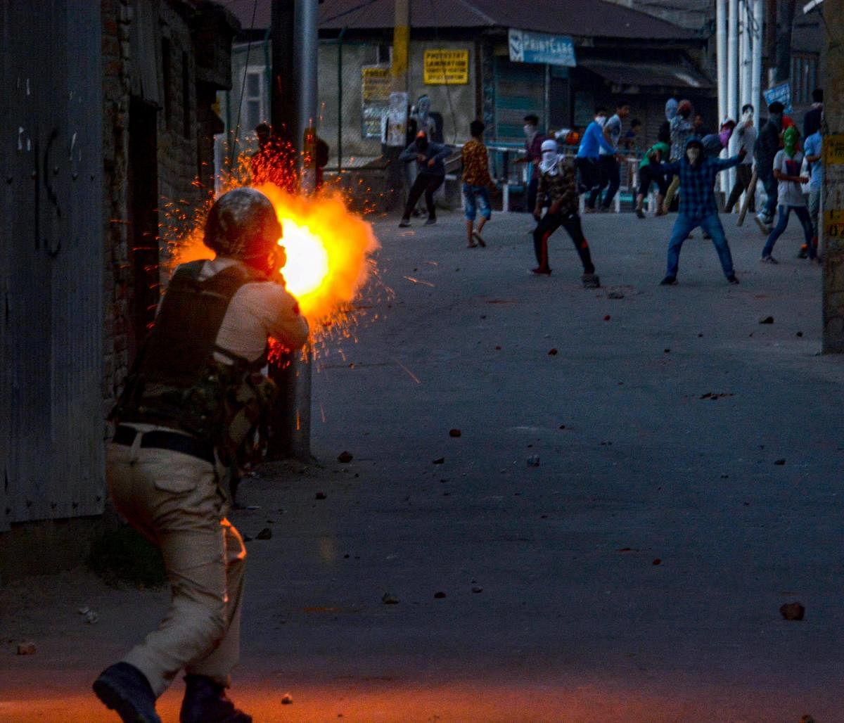 A policeman fires tear gas shells at protesters hurling stones during a protest against the killing of three Kulgam civilians, in Srinagar on Saturday. PTI