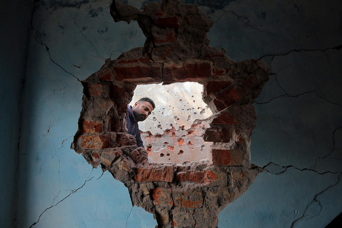 A man looks at the wall of his house that the local residents say was damaged by firing from the Pakistan side of the border at Kanachak in Akhnoor Sector on the outskirts of Jammu January 22, 2018.