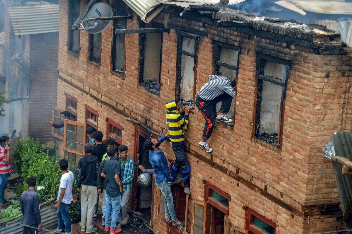 People inspect the damaged house where four militants were killed during an encounter at Srigafwara in Anantnag district of south Kashmir on Friday. PTI