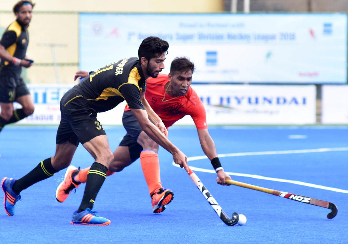 IOCL's Vikramkanth (right) and PNB's Shamsher Singh vie for the ball during their clash in the 2nd Bengaluru Super Division Hockey League on Thursday. DH Photo