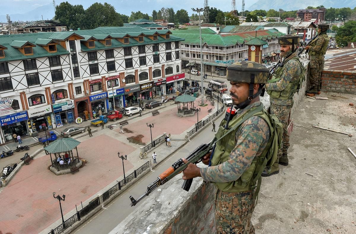 CRPF personnel take a position on the top of a building during a random search operation at Lal Chowk in Srinagar, on Friday. Security has been in on high alert after recent attacks by suspected militants in Srinagar. PTI