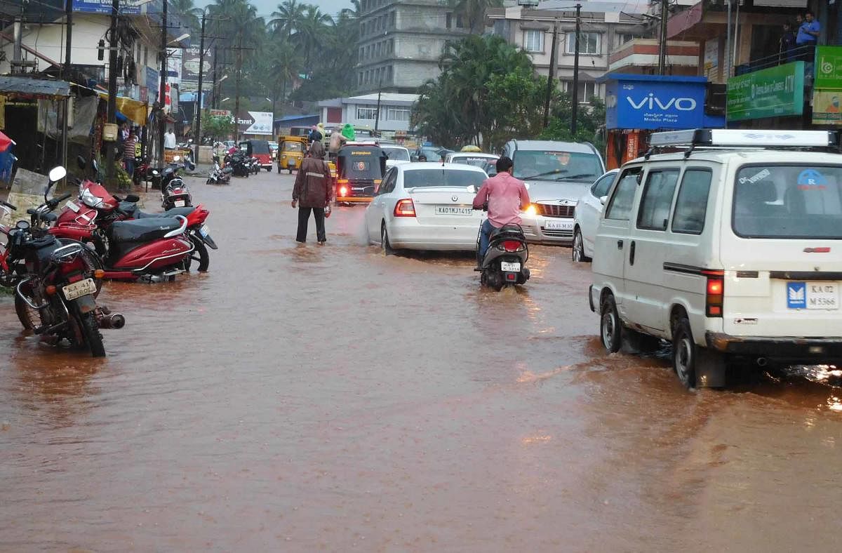 Vehicles navigate on a waterlogged road in Sirsi, Uttara Kannada district on Friday. DH Photo