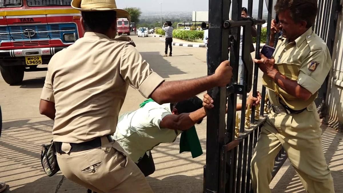 A sugarcane farmers tries to break the police cordon in Belagavi, on Sunday. DH photo.