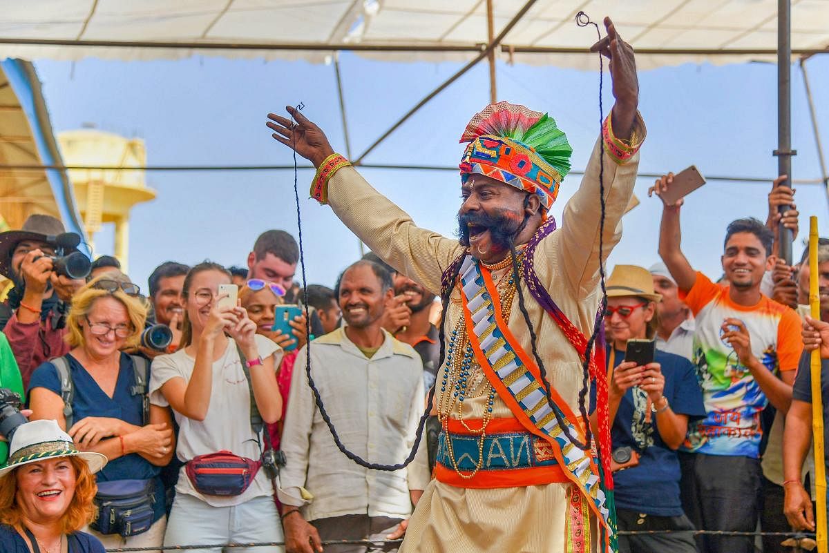 A local artist entertains tourists with his moustache at Pushkar Camel Fair, in Pushkar, Rajasthan on Tuesday. PTI