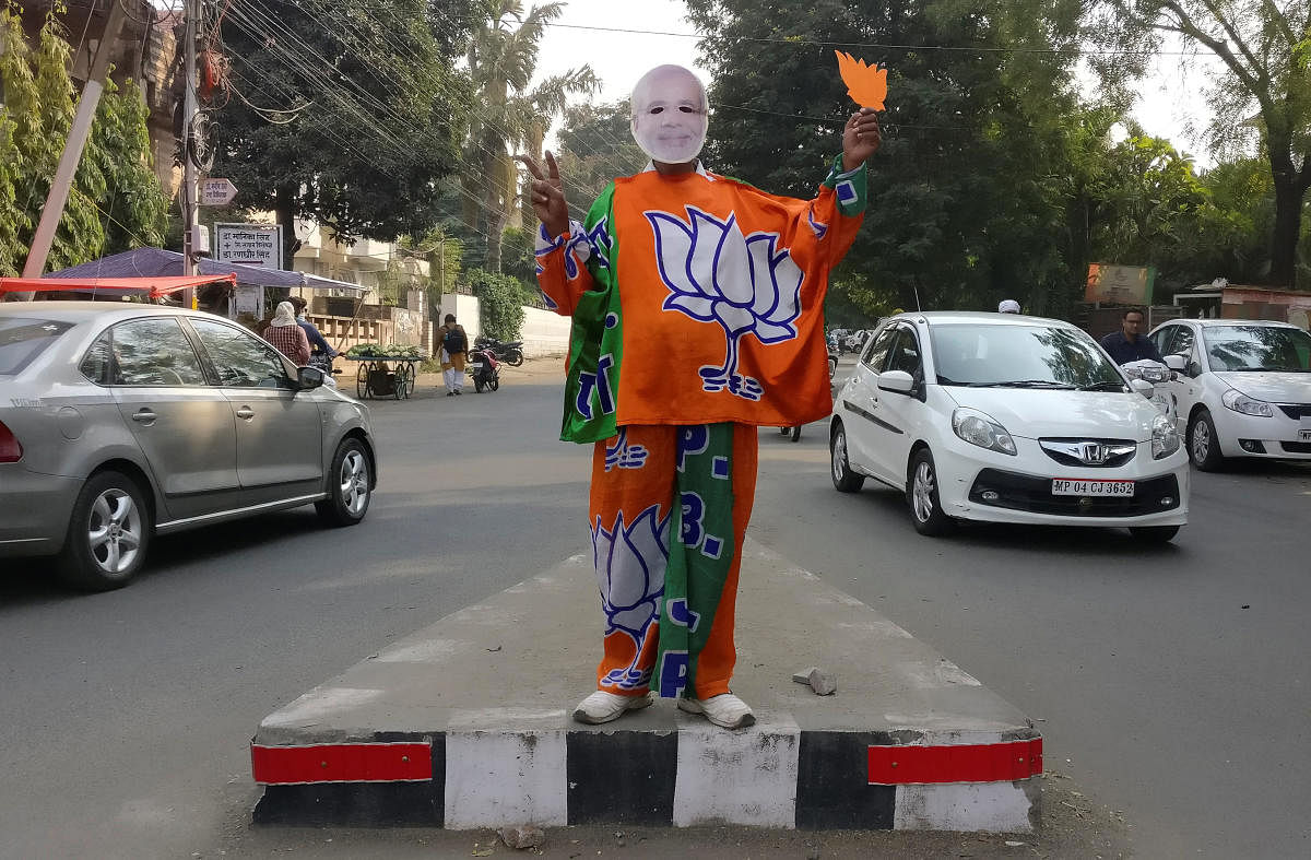 REFILE - REMOVING ERRONEOUS INFORMATION A supporter of India's Bharatiya Janata Party (BJP) wears a mask depicting the Indian Prime Minister Narendra Modi, and drapes himself with flags of BJP's symbol at a traffic signal in Bhopal, India, November 20, 20