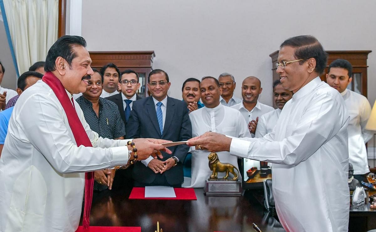 Former Sri Lankan president Mahinda Rajapakse (L) handing over documents to Sri Lankan President Maithripala Sirisena (R) as Rajapakse is sworn in as new Prime Minister, in Colombo. (Photo by Handout / Sri Lanka President Media / AFP)