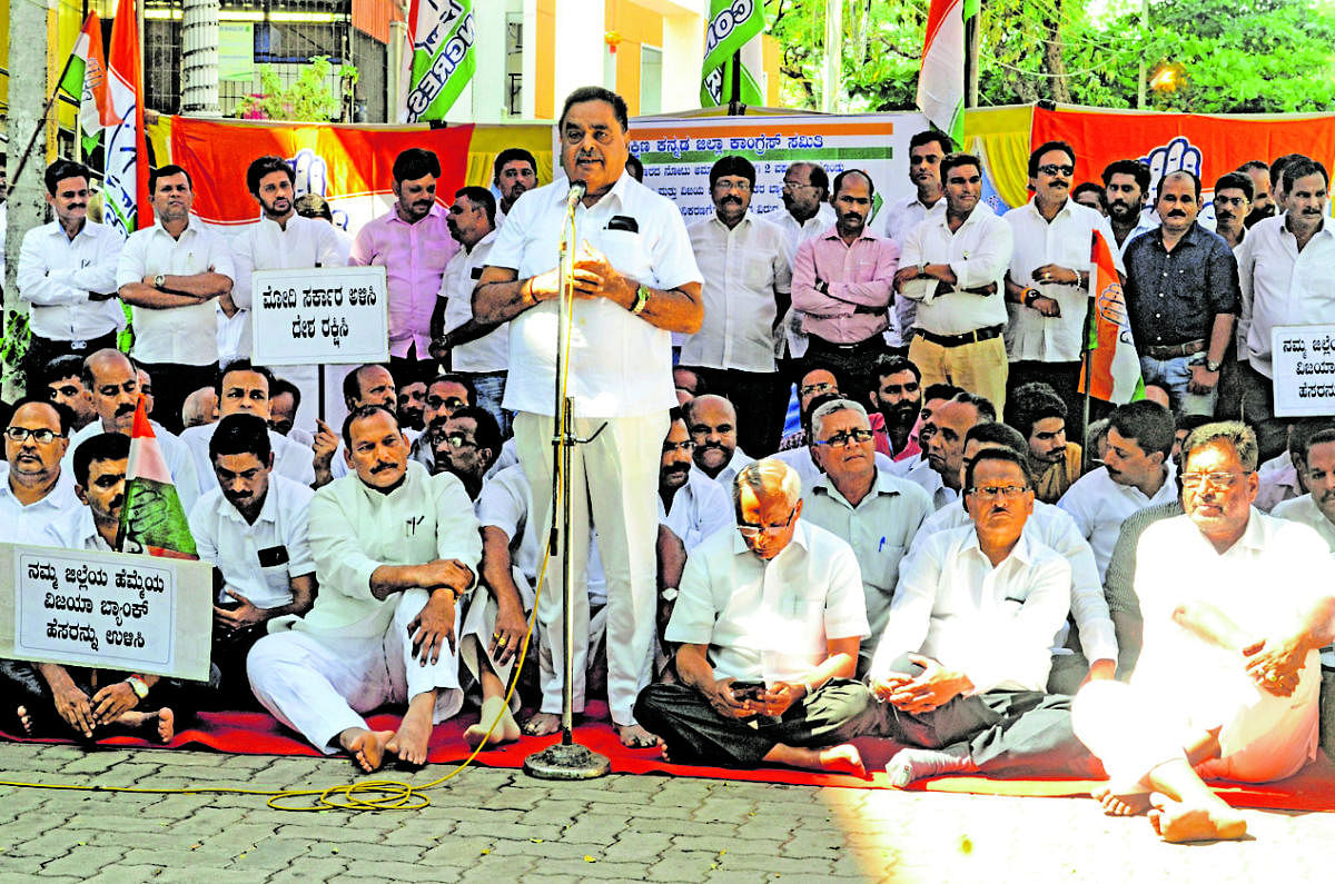 Former minister B Ramanath Rai addresses the protest organised by the District Congress Committee, to mark the second anniversary of demonetisation and proposed merger of Vijaya Bank, in front of the DCC office in Mallikatte in Mangaluru on Friday.