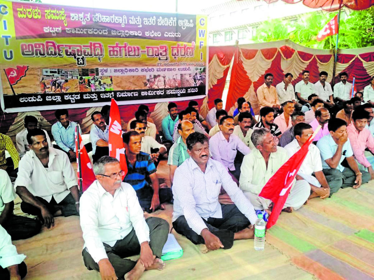 Udupi District Building and Other Construction Workers' Coordination Committee members stage a stir in front of the DC's office in Manipal on Tuesday.