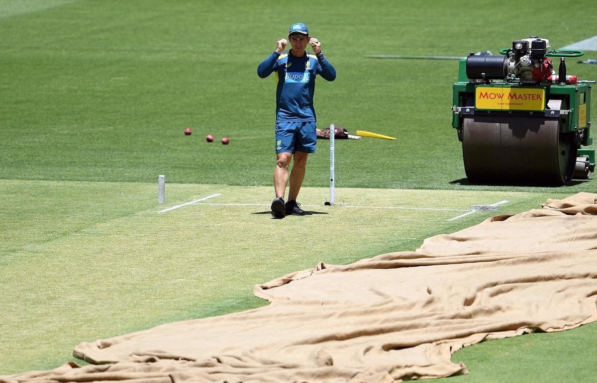 Australia's coach Justin Langer inspects the Optus Stadium pitch that has a lot of grass in it and promises to be fast and bouncy one. AFP