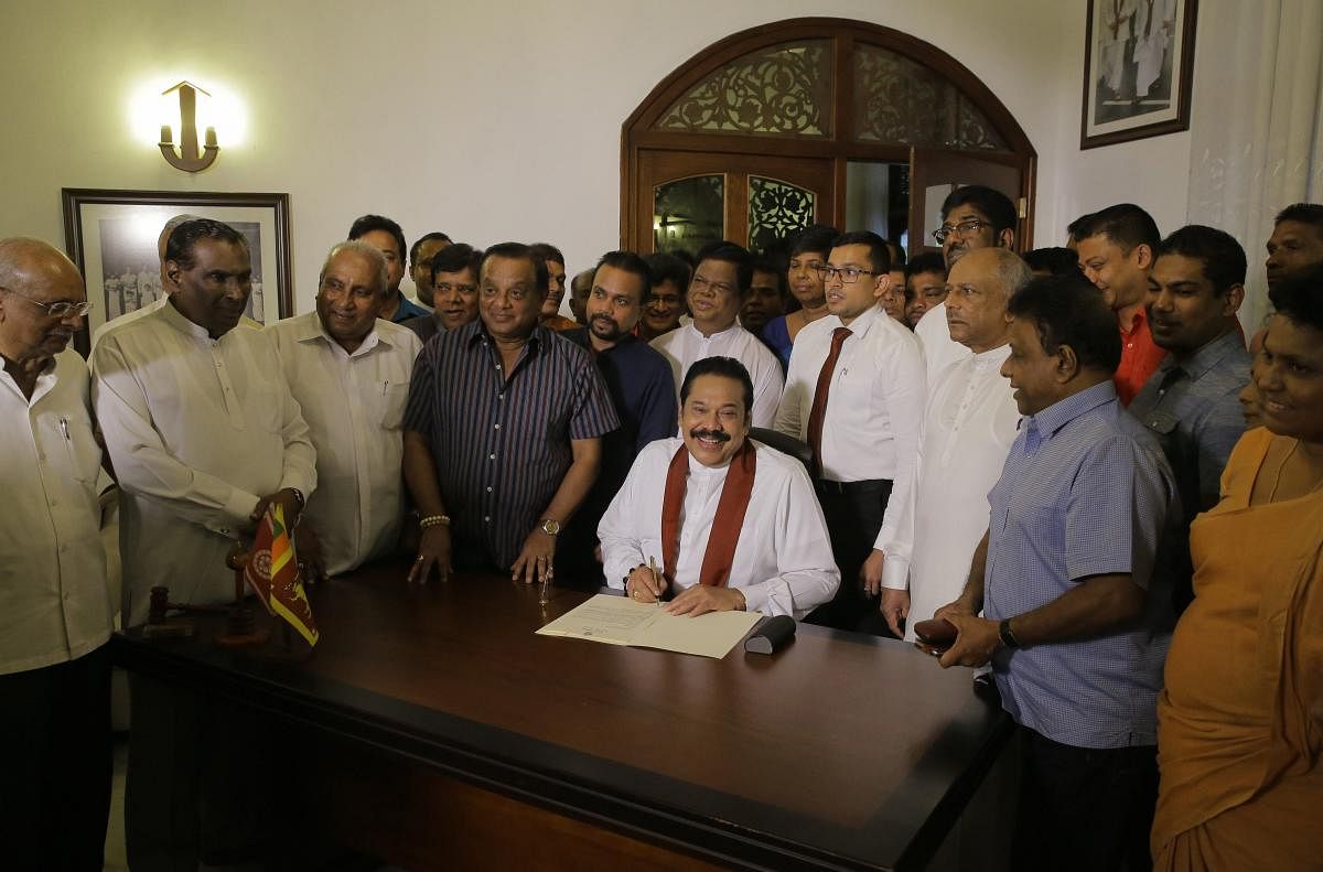 Sri Lanka's disputed Prime Minister Mahinda Rajapaksa signs his resignation letter at his residence in Colombo, Sri Lanka, Saturday. AP/PTI photo