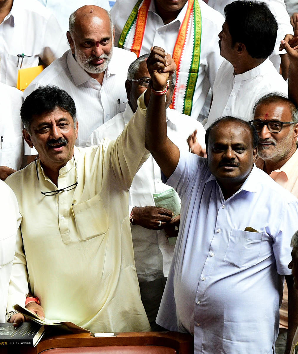 Congress leader D K Shivakumar and JD(S) leader H D Kumaraswamy raise their arms in a show of unity after winning the vote of confidence in the Karnataka Assembly. (DH Photo)