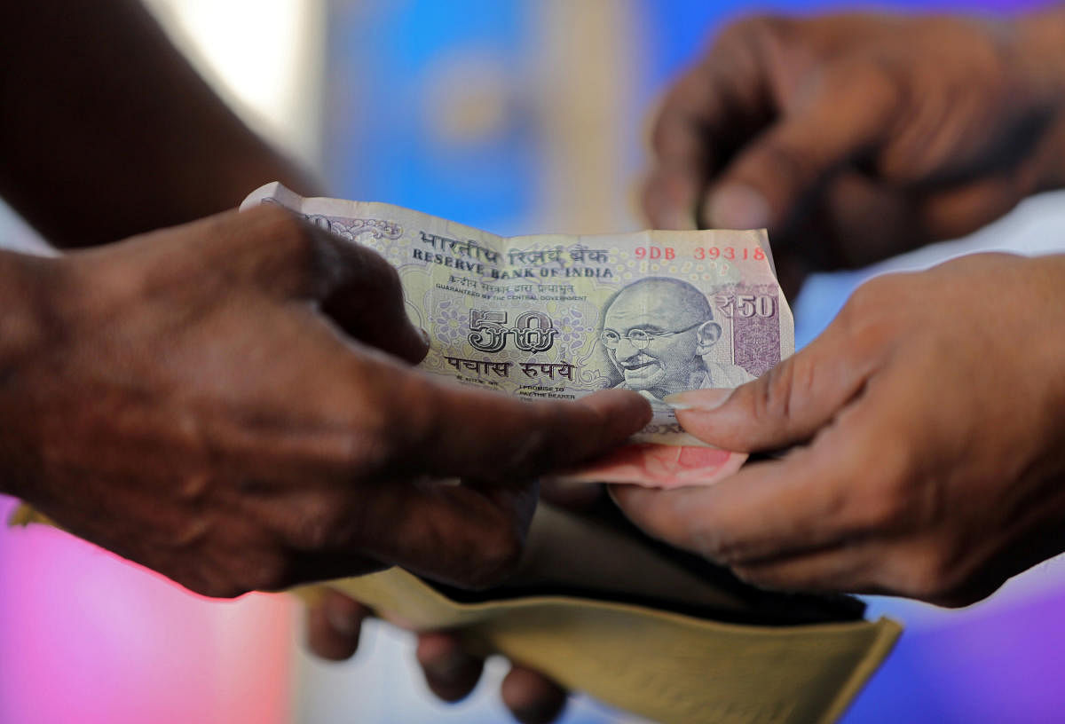 A customer hands a 50-Indian rupee note to an attendant at a fuel station in Ahmedabad. REUTERS