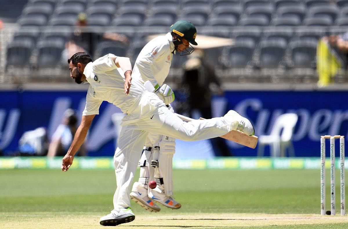 India's bowler Mohammed Shami (L) attempts to field the ball as Australia's batsman Usman Khawaja runs back to the crease during day four of the second Test cricket match between Australia and India in Perth. AFP Photo
