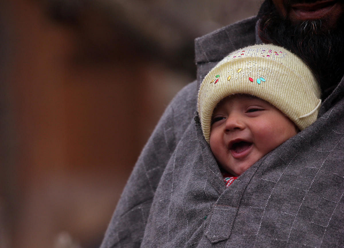 A man carries an infant on a cold winter day in a village of south Kashmir's Pulwama district. (REUTERS Photo)