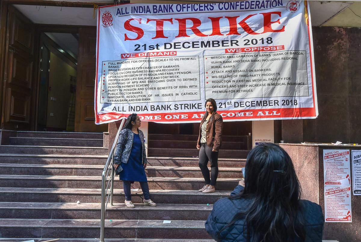 Bank employees click photos outside a closed bank office during a nationwide strike called by All India Bank Officers' Confederation (AIBOC), in New Delhi, Friday (PTI Photo)