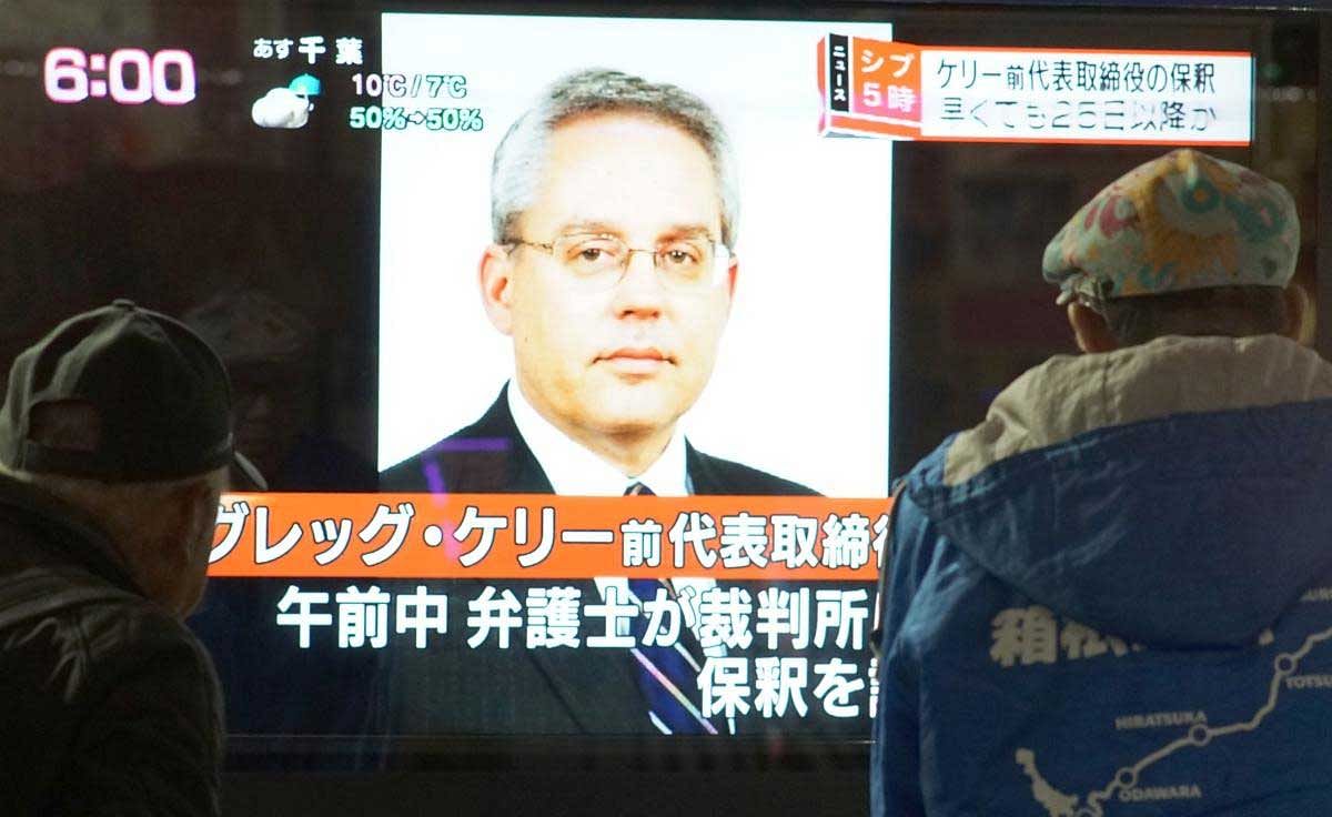 This picture taken on December 21, 2018 shows pedestrians looking at a television news program featuring former former Nissan representative director Greg Kelly in Tokyo. - Japanese authorities suspect former Nissan boss Carlos Ghosn conspired with his right-hand man Kelly to hide away around half of his income (some five billion yen or $44 million) over five fiscal years from 2010. (AFP Photo)