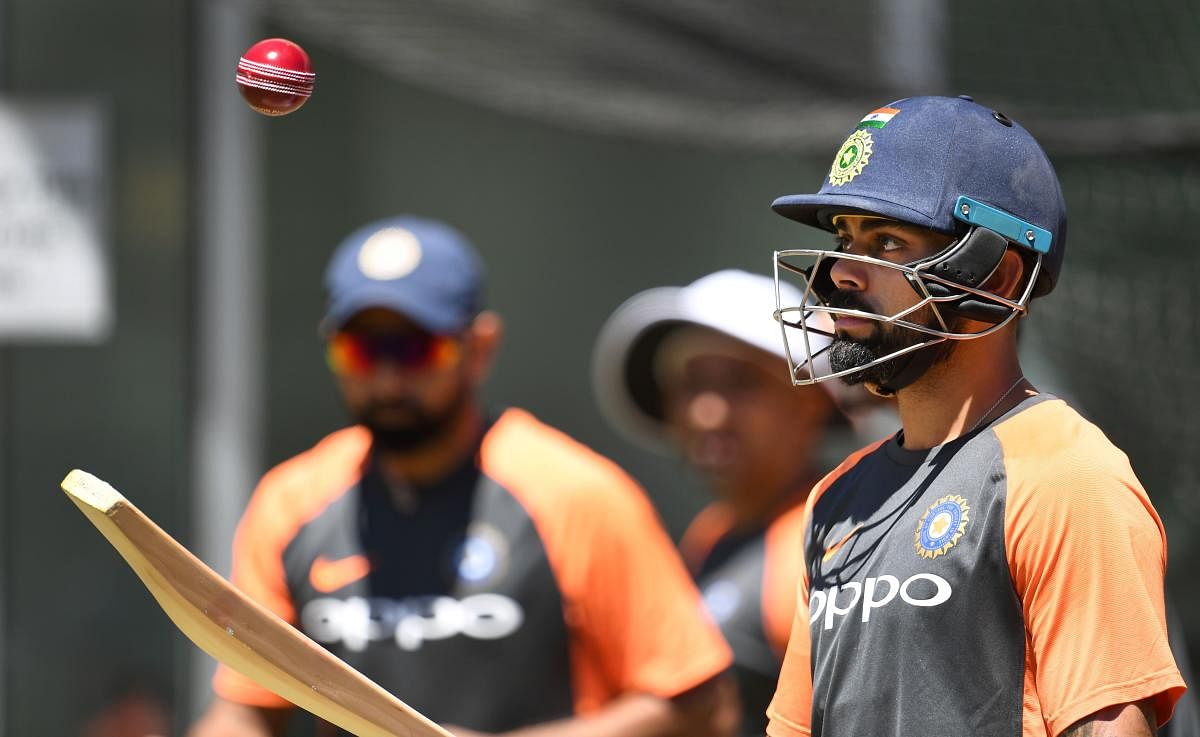 India's captain Virat Kohli (R) hits a ball in the air during a training session in Melbourne on December 24, 2018, ahead of the third cricket Test match against Australia. (AFP Photo)
