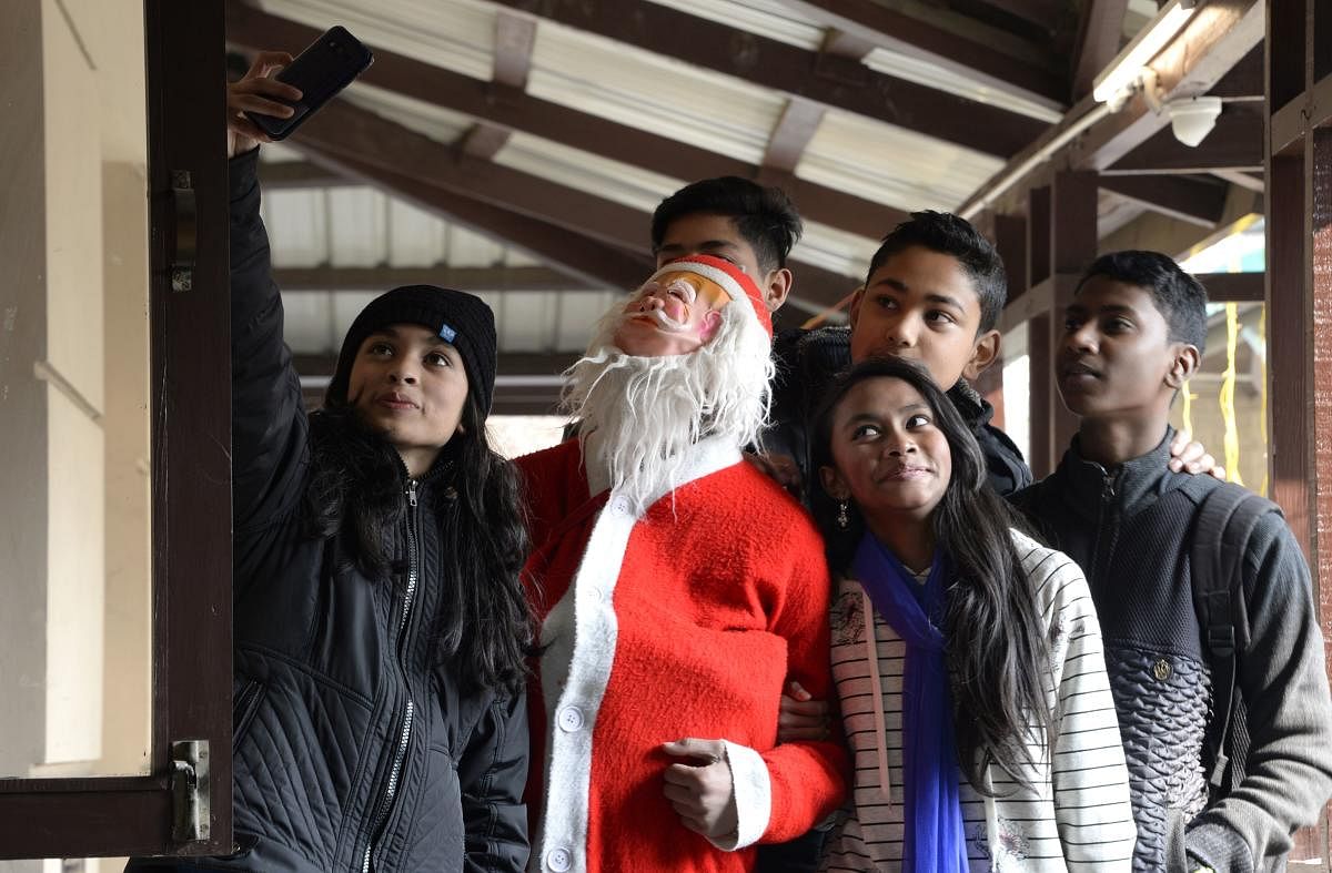 Youths take a selfie with a Santa Claus figure during a Christmas Day service at a Catholic church in Srinagar on Tuesday. AFP
