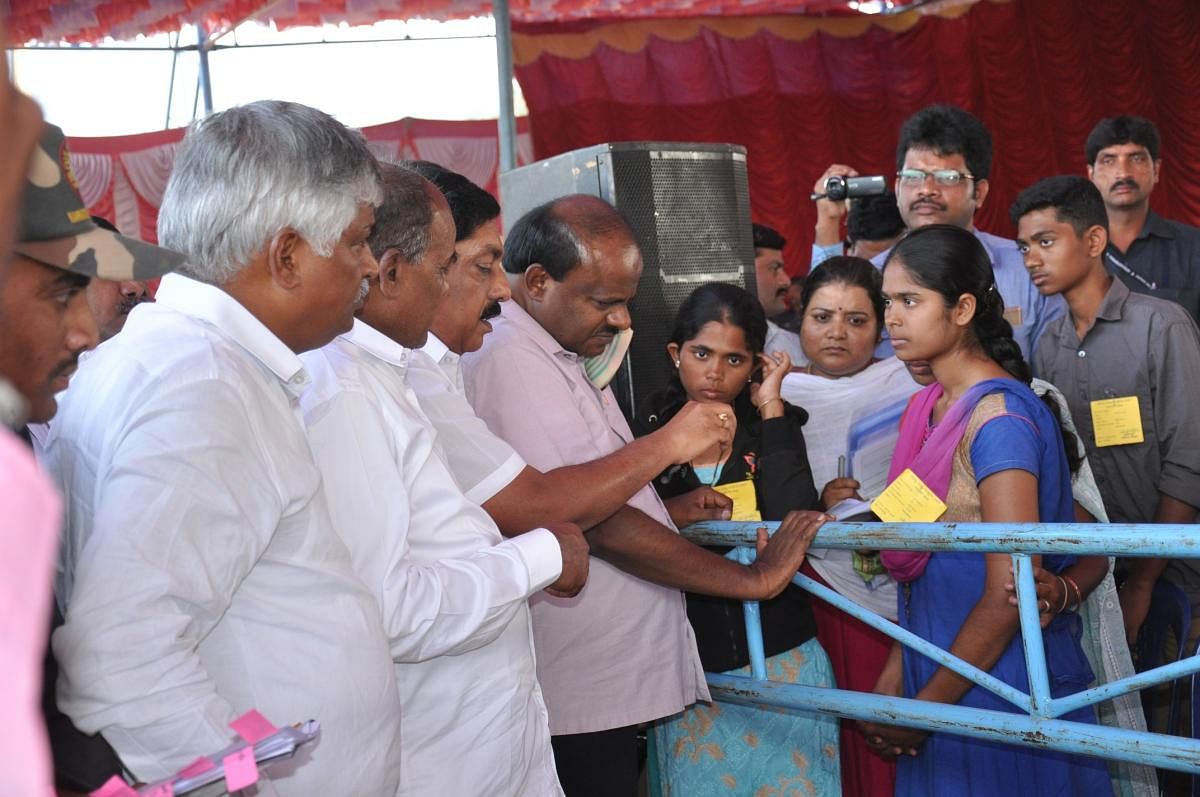 Chief Minister H D Kumaraswamy interacts with the daughters of prasdam victims Mylibai and Krishnanayaka, during his visit to Sulvadi village, Hanur taluk, Chamarajanagar district, on Tuesday.