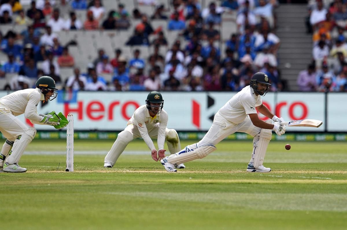 India's batsman Rohit Sharma (R) plays a defensive shot as Australia's wicketkeeper Tim Paine (L) looks on during day two of the third cricket Test match between Australia and India in Melbourne on December 27, 2018. (AFP Photo)