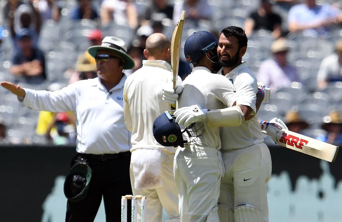 India batsman Cheteshwar Pujara (R) celebrates his century with teammate Virat Kohli on day two of the third Test against Australia in Melbourne on December 27, 2018. (AFP Photo)