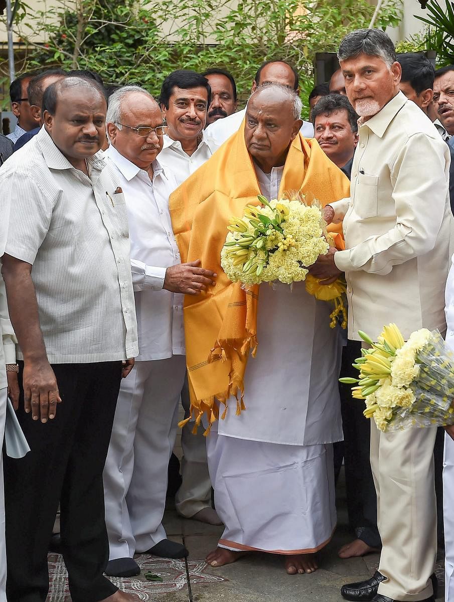 Andhra Pradesh Chief Minister N Chandrababu Naidu (R) presents a bouquet to former prime minister HD Devegowda as Karnataka Chief Minister HD Kumaraswamy (L) looks on, before a meeting in Bengaluru on Thursday. PTI