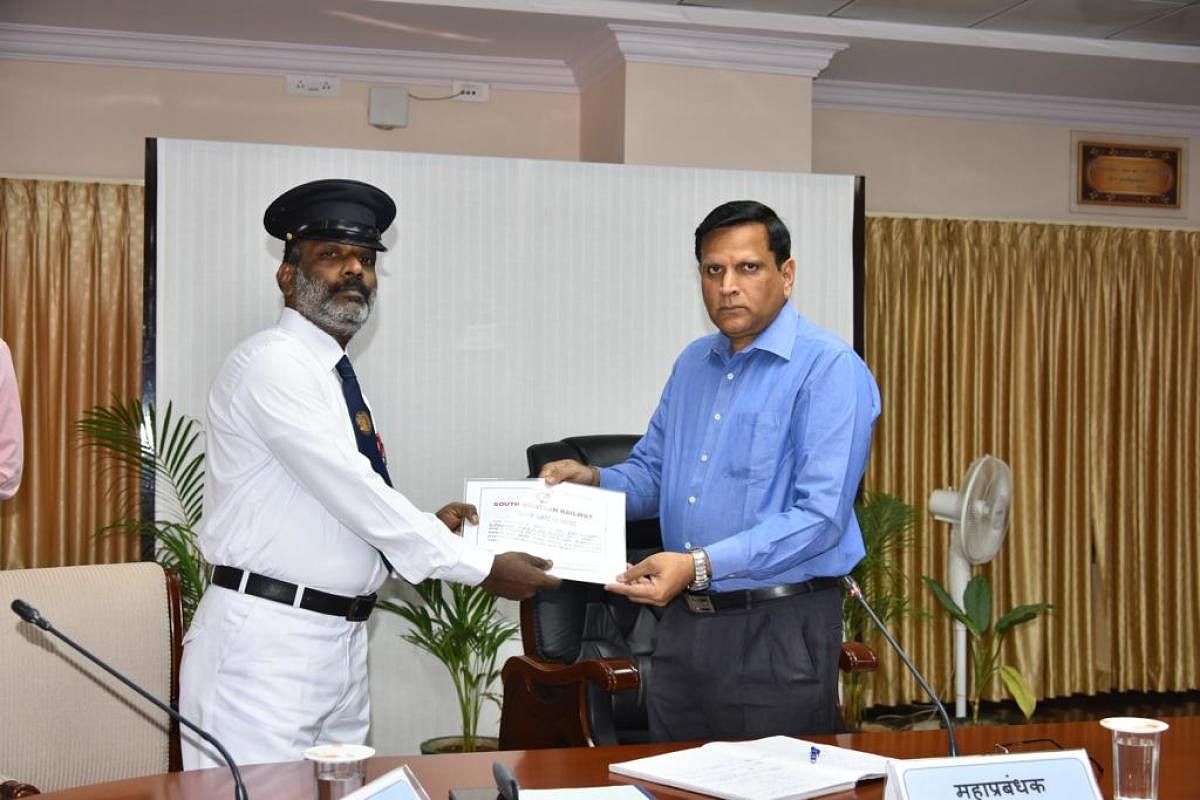 N Vishnoomurthy, senior passenger guard, receives a certificate from Ajay Kumar Singh, General Manager, South Western Railway, on Monday. 