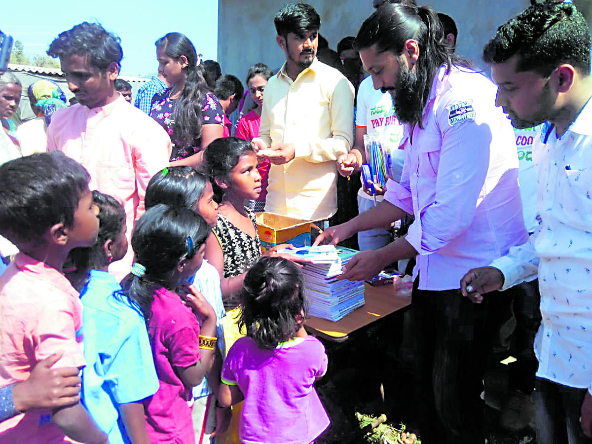 Actor Chetan distributes stationary items and sweets to the children at the Diddalli evacuees rehabilitation centre in Byadagotta near Kushalnagar.