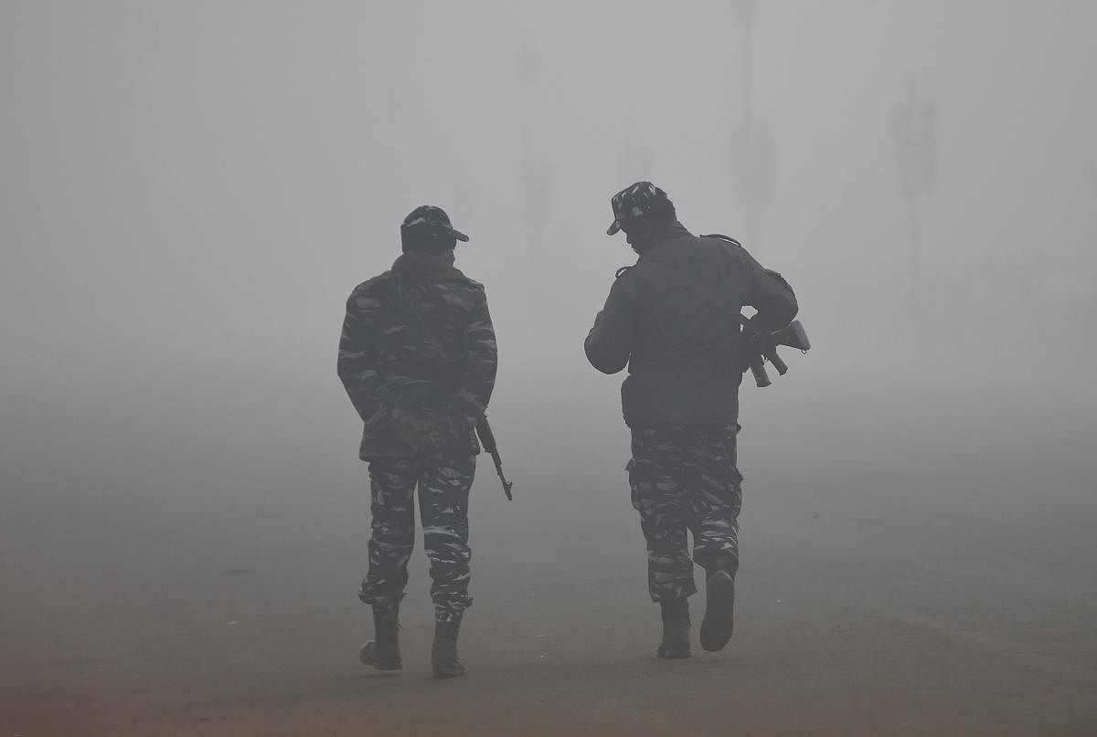 Indian security forces walk amid heavy fog and smog conditions in New Delhi on January 3, 2019. (Photo by Money SHARMA / AFP)