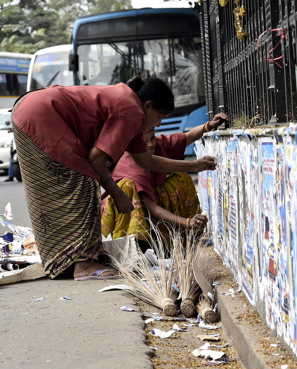 BBMP workers remove posters pasted on the walls of government buildings at KR Circle. DH file photo